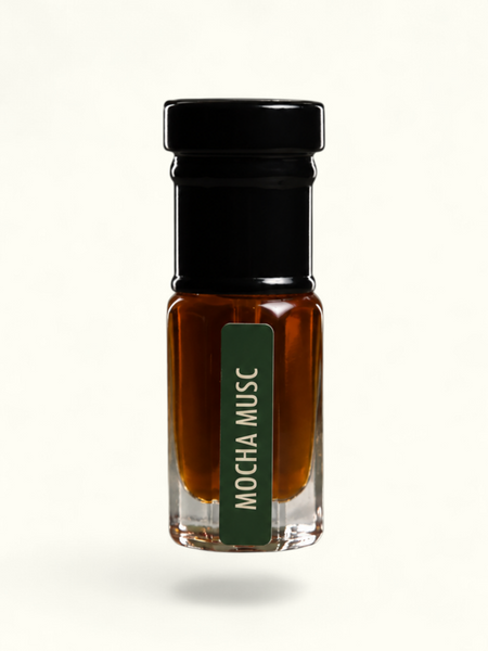A small clear glass bottle filled with amber-brown liquid, topped with a black cap, and featuring a dark green vertical label that reads 'MOCHA MUSC' in white text, centered on a plain off-white background.