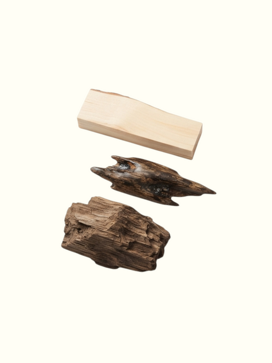 A perfume fragrance card for 'Regal Assam' from Eaux de Parfum, showing three natural wood pieces (a rectangular block and two textured driftwood pieces) on the left, with descriptive text on the right detailing the scent profile from top to base.